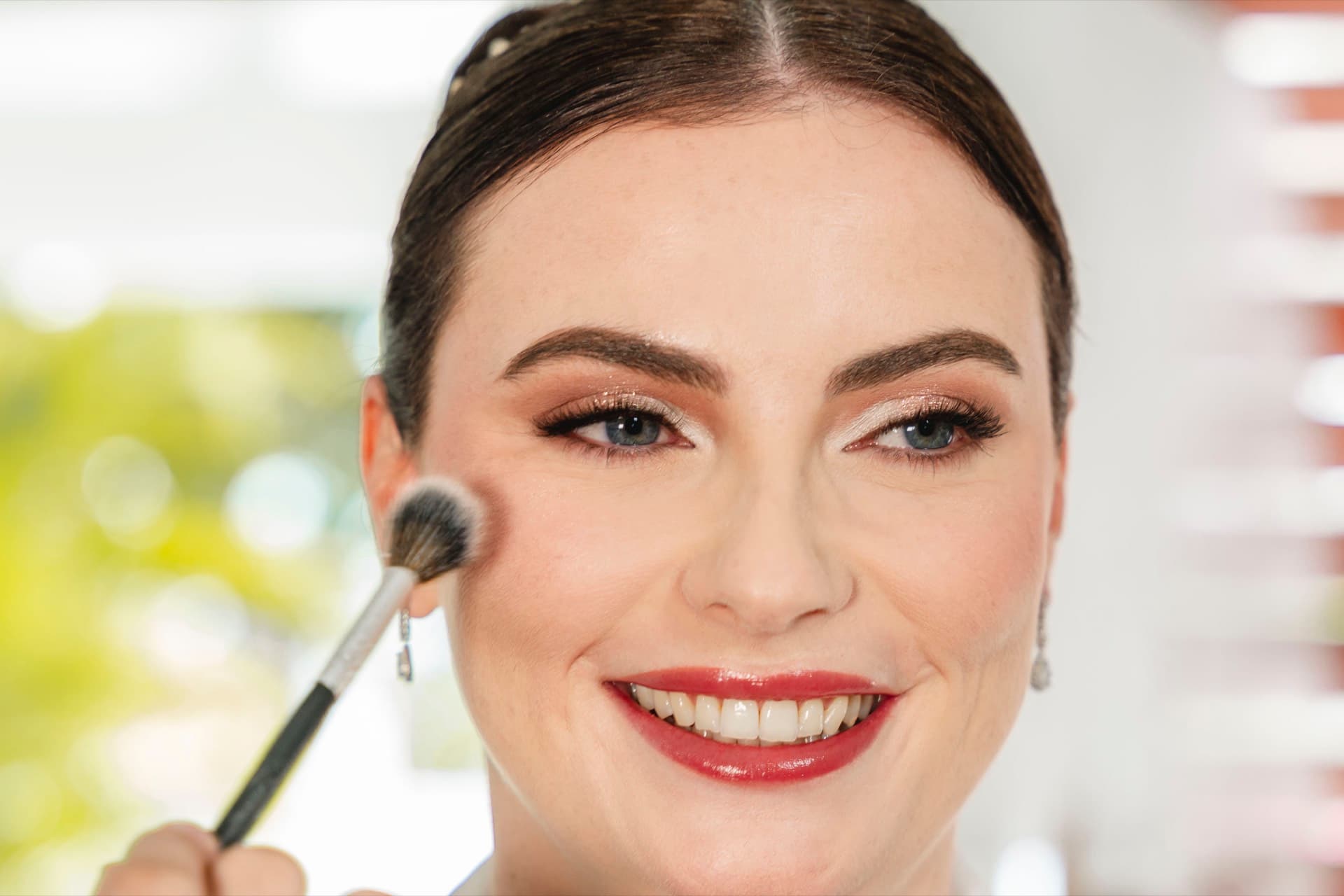 Novia sonriendo mientras le aplican maquillaje